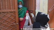 A health worker (R) inoculates a woman with a dose of the Covid-19 coronavirus PakVac vaccine during door to door vaccination in Karachi on January 11, 2022. (Photo by Rizwan TABASSUM / AFP) (Photo by RIZWAN TABASSUM/AFP via Getty Images)