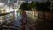 A man wades through flood waters in Jakarta, traffic and the illuminated city can be seen behind him A man wades through flood waters in Jakarta, traffic and the illuminated city can be seen behind him