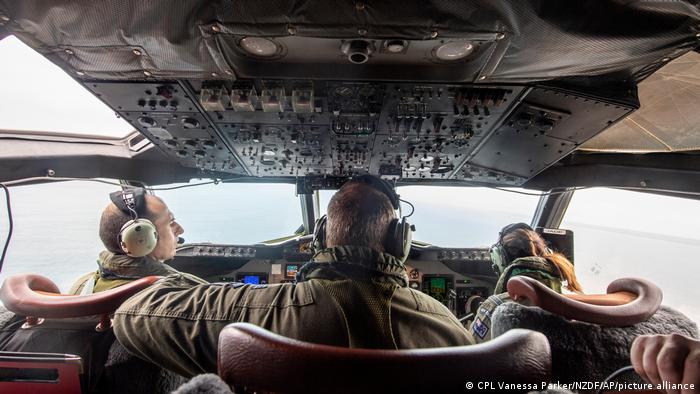 In this photo provided by the New Zealand Defense Force, the crew from an Orion aircraft look out the window as it flies over an area of Tonga that has heavy ash fall from a volcanic eruption 