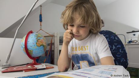 Ein Grundschüler löst an seinem Schreibtisch Mathematik-Hausaufgaben
