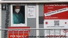 A woman looks through a window of a portable coronavirus testing cabin set up in Berlin