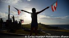 17.07.2019
A protester waves flags at the start of a protest against Gov. Ricardo Rosselló at Quinto Centenario Plaza in San Juan, Puerto Rico, Wednesday, July 17, 2019. Protesters are demanding Rosselló step down for his involvement in a private chat in which he used profanities to describe an ex-New York City councilwoman and a federal control board overseeing the island's finance. (AP Photo/Carlos Giusti)
