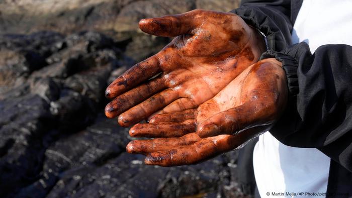 Foto simbólica de una persona que muestra sus manos llenas de petróleo.