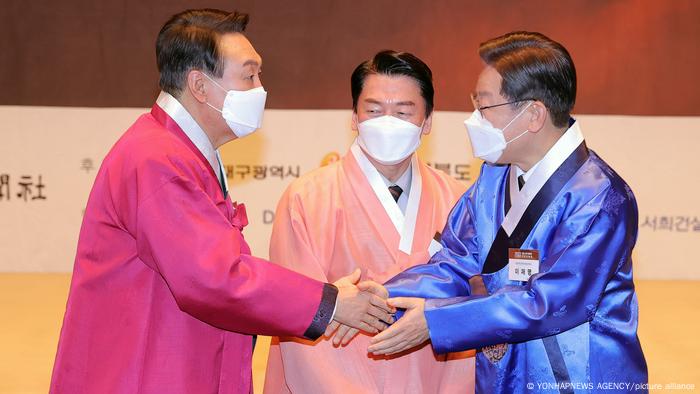 Presidential candidates Lee Jae-myung (R), the presidential candidate of the ruling Democratic Party, shakes hands with rival Yoon Suk-yeol (L) of the main opposition People Power Party, with Ahn Cheol-soo, the nominee of the minor People's Party, watching.