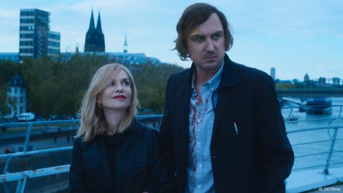 Isabelle Huppert dan Lars Edinger dalam sebuah adegan dari film - Pertunjukan De Joanne di dekat Katedral Cologne yang dapat dilihat di latar belakang