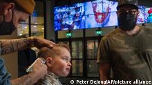 Three-year-old Ole van Santen gets a haircut at the Van Gogh museum in Amsterdam, Wednesday, Jan. 19, 2022, as Dutch museums, theaters and concert halls played host Wednesday to businesses that are allowed to open to customers as a protest against their own continuing lockdown closures. (AP Photo/Peter Dejong)