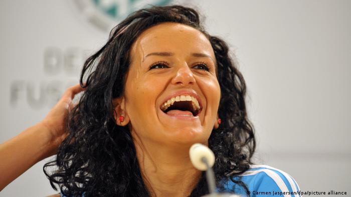 Lira Bajramaj bei einer Pressekonferenz lachend vor einem Mikrofon