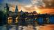 A stone bridge (Charles Bridge) and the Prague city skyline are seen from the Vltava River at sunrise A stone bridge (Charles Bridge) and the Prague city skyline are seen from the Vltava River at sunrise