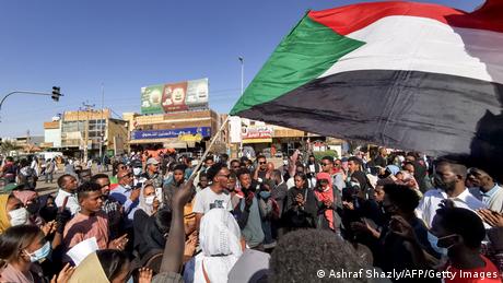 Protesters take to the streets of the Sudanese capital Khartoum. A large Sudanese flag is seen. 