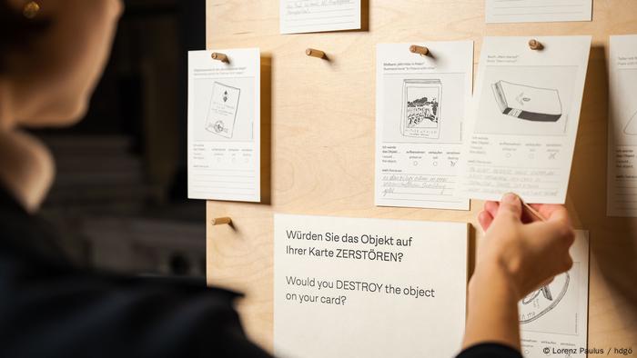 Visitor pulling at card, with various cards hanging on board.