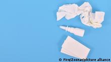 Top view of nasal spray bottle and used tissues used during common cold on blue background