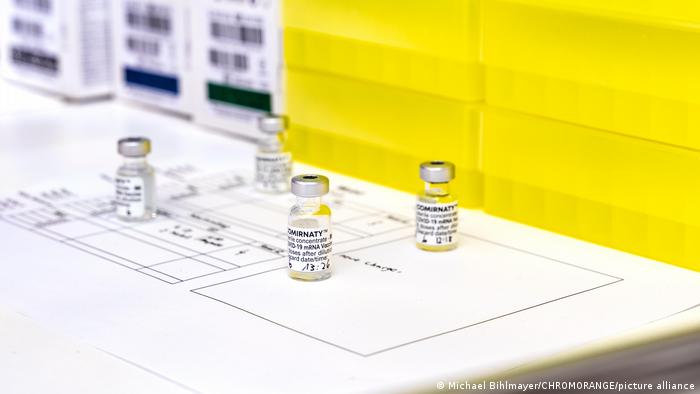 Four vials of vaccine sit on a white paper with technical indications