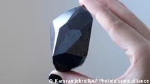 Un empleado de Sotheby's Dubai presenta el diamante negro de 555,55 quilates conocido como Enigma.