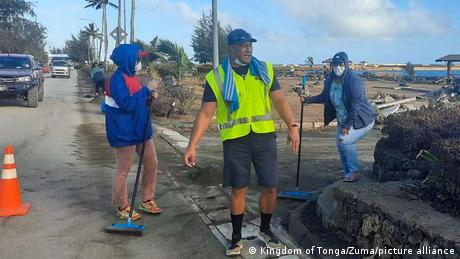 People sweep ash from a street in Tonga