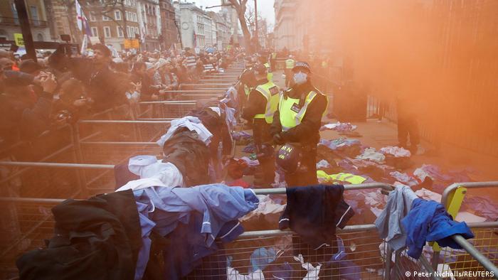 UK police officers stand amid smoke and medical uniforms during a rally against vaccine rules in London