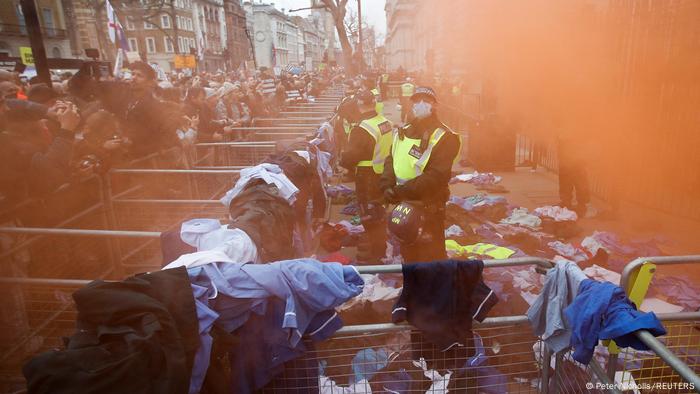 Britische Polizisten stehen während einer Kundgebung gegen Impfvorschriften in London inmitten von Rauch und medizinischen Uniformen