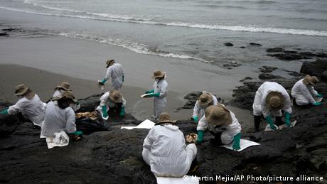 Workers clean oil on Cavero Beach in the Ventanilla district of Callao, Peru