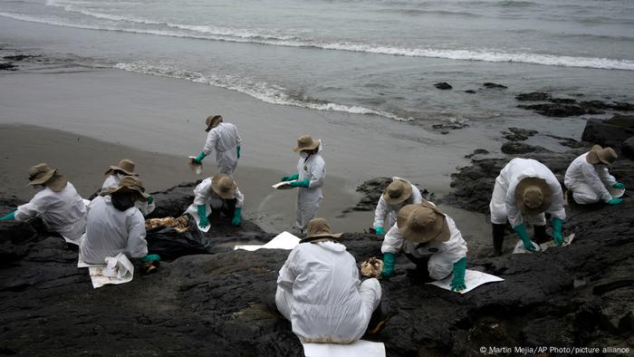 Workers clean oil at a Peruvian beach