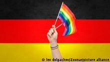 lgbt, same-sex relationships and homosexual concept - close up of male hand wearing gay pride awareness wristband holding rainbow flags over german flag background