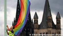 Una bandera arco iris es izada a la vista de la Catedral de Colonia y de la Iglesia de San Martín.