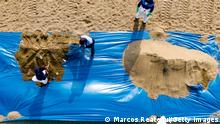 VENTANILLA, PERU - JANUARY 20: Aerial view as Repsol employees load up sand during the clean-up of an oil spill at Bahía Blanca beach on January 20, 2022 in Ventanilla, Peru. Waves attributed to the eruption of underwater volcano Hunga-Tonga-Hunga-Ha'apai in Tonga produced an oil spill in the coast of Lima. According to information released by Peruvian Civil Defense Institute, a ship of Repsol was loading oil into La Pampilla refinery on January 16 when strong waves pushed the boat causing the spill, considered the worst ecological disaster in Peruvian recent history. (Photo by Marcos Reategui/Getty Images)