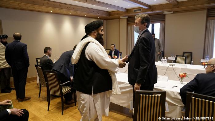El ministro de Exteriores afgano, Amir Khan Muttaqi, estrecha la mano del representante británico, Nigel Casey.