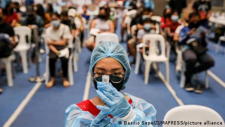 A health worker transfers a dose of Moderna's COVID-19 vaccine into a syringe during an inoculation drive in Manila
