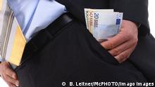 Symbolbild | Korruption | Hand schiebt Geld in die Tasche