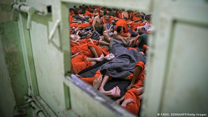 Men, suspected of being affiliated with the Islamic State (IS) group, gather in a prison cell in the northeastern Syrian city of Hasakeh