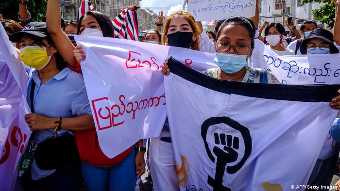 Women carry banners as they march during a demonstration against the military coup in Yangon on July 14, 2021