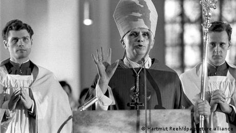 Joseph Ratzinger hält 1977 nach seiner Wahl zum Erzbischof eine Rede, links und rechts von ihm stehen zwei Geistliche.