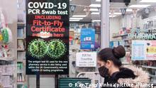 (211207) -- LONDON, Dec. 7, 2021 (Xinhua) -- A woman wearing a face mask walks past a COVID-19 PCR Swab Test sign in London, Britain on Dec. 6, 2021. A further 90 cases of the new Omicron COVID variant have been reported in Britain, taking the total to 336, British health authorities confirmed Monday. Britain registered 51,459 new COVID-19 infections, bringing the total number of coronavirus cases in the country to 10,515,239, according to official figures released on Monday. (Photo by Ray Tang/Xinhua)