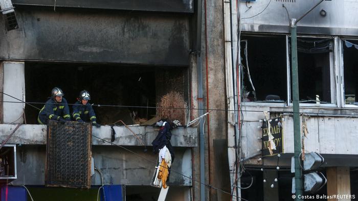 Firefighters work inside a building after a blast in Athens
