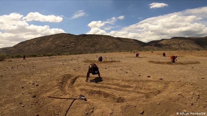 Person digging depressions into the soil in Tanzania