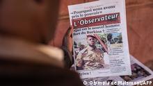 A man buys a newspaper with theh the picture of Paul-Henri Sandaogo Damiba the leader of the mutiny and of the Patriotic Movement for the Protection and the Restauration (MPSR) in Ouagadougou on January 25, 2022. - In the aftermath of the coup d'etat in Burkina Faso which overthrew President Roch Marc Christian Kaboré, a demonstration in support of the putschists is scheduled for Tuesday in Ouagadougou where calm has returned after days of tension. (Photo by OLYMPIA DE MAISMONT / AFP)