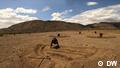 Tanzania: People dig a fallow soil with the hills in the background, clouds in the sky