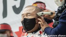 A South Korean businessman gets his head shaved in protest of the government's COVID restrictions