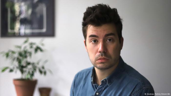 Hungarian investigative journalist Szabolcs Panyi, in a blue shirt with plant in the background.