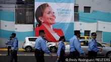 26.1.2022, Tegucigalpa, Honduras, Honduras police officers walk past a poster with an image of Xiomara Castro outside the National stadium, during the preparations of event areas and security ahead of the swearing-in ceremony of Honduras' President-elect Xiomara Castro in Tegucigalpa, Honduras January 26, 2022. REUTERS/Fredy Rodriguez