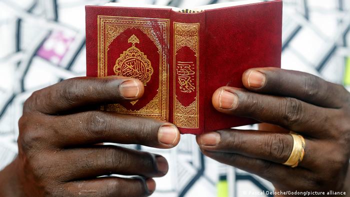 A photograph of a man's hands holding the Quran