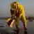 Eine Person in gelber Schutzkleidung reinigt den Strand