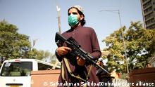 Ein Taliban-Kämpfer trägt einen Mund-Nasen-Schutz und steht mit einem Gewehr in der Hauptstadt. Nach Angaben des Taliban-Sprechers Mudschahid wurden die Einwohner aufgefordert, Fahrzeuge, Waffen und Munition der Regierung zu übergeben. +++ dpa-Bildfunk +++