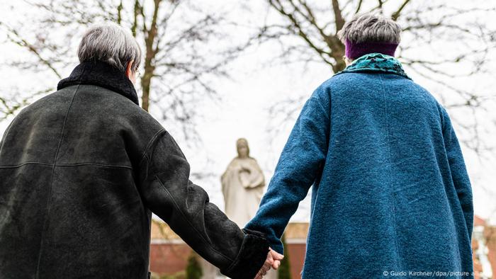 A same-sex couple in front o a state of Maria