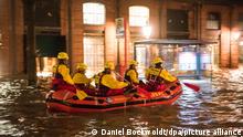 Mitglieder der DLRG üben am unter Wasser stehenden Fischmarkt mit der Fischauktionshalle an der Elbe während einer Sturmflut den Umgang mit ihrem Boot.