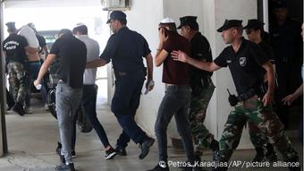 Israeli teenagers pictured covering up their faces as security personnel guide them outside a district court in Cyprus in July, 2019