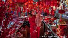BEIJING, CHINA - JANUARY 29: A woman carrying a child wear protective masks as they look at decorations for sale for the upcoming Chinese New Year and Spring Festival at a market on January 29, 2022 in Beijing, China. China will celebrate the Lunar New Year and the Year of the Tiger on February 1. (Photo by Kevin Frayer/Getty Images)