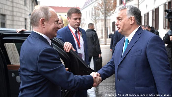 Russian President Vladimir Putin (left) shakes hands with Viktor Orban on a street in Budapest