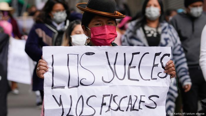 Una mujer sostiene un cartel que reza los jueces y los fiscales son corruptos durante una protesta en La Paz, Bolivia.
