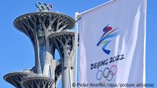 Blick auf den Olympiaturm und eine Fahne mit dem Logo der olympischen Spiele 2022. Die Olympischen Winterspiele in Peking finden vom 04.-20.02.2022 unter strengen Corona-Auflagen statt.