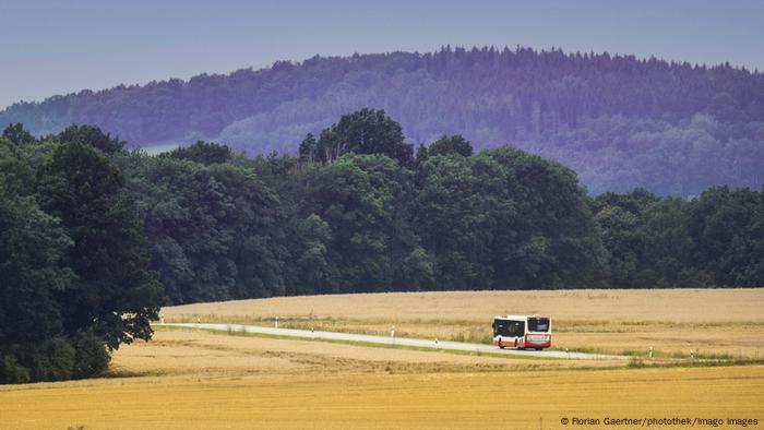 A public bus drives down a country road in Saxony, Germany